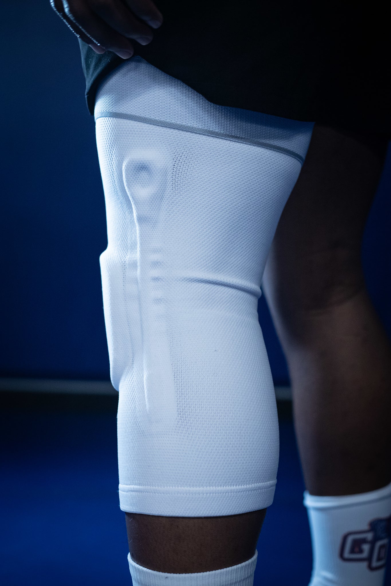 White knee pad worn by a person on a blue background